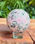 Polished multicolored stone sphere on a wooden surface with a natural background