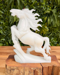 White jade  horse sculpture on a wooden block with a green leafy background